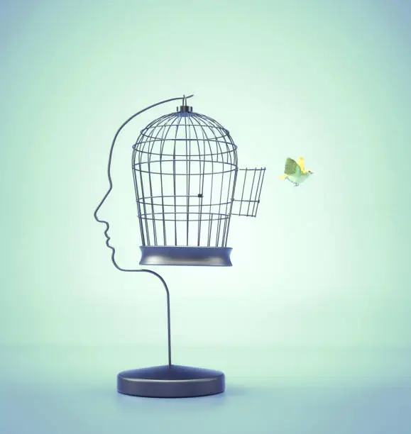 Bird flying off a bird cage shaped as a head. Ideas and happiness concept. This is a 3d render illustration