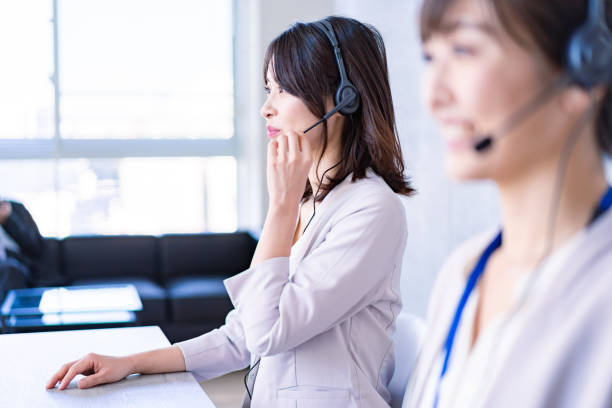 operator answering the phone with a smile - hotel reception customer service representative headset receptionist imagens e fotografias de stock