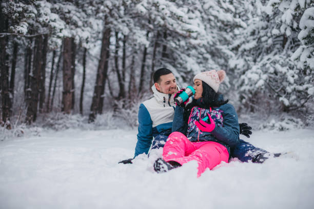 istock A young couple is sitting on the snow drinking tea from a thermos 1365371088