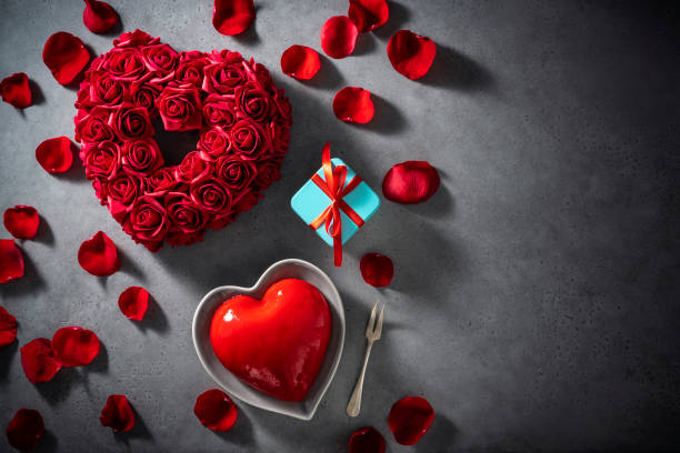 istock Valentines red rose flower petals and heart shape cake on gray copy space 1365372048