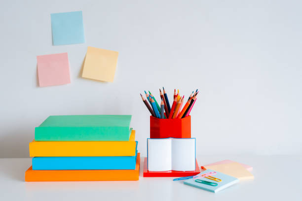 Student creative desktop layout with colorful stationery, colored pencils and bright books on a white wall background. Back to school. free space
