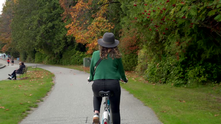 Beautiful Young Woman Cycling Around Stanley Park By Day in Fall Season in Vancouver, British Columbia, Canada