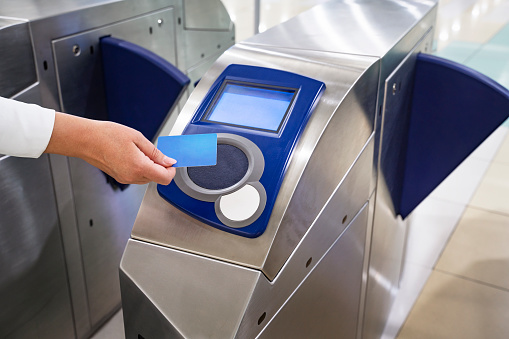 Close-up hand with keycard at pedestrian access control flap barriers