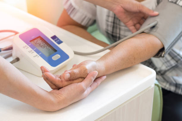 caregiver che controlla la pressione arteriosa del paziente di sesso femminile anziano con manometro sfigmomanometro a braccio digitale. concetto medico e sanitario. - patient blood pressure gauge doctor male foto e immagini stock