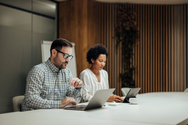 istock Two serious colleagues, concentrating on their work in the office. 1365384370