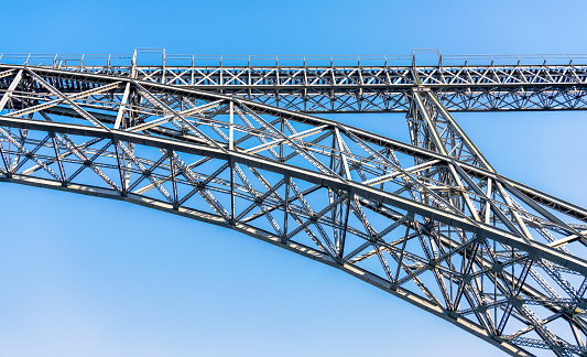 A close-up of the intricate steelwork making up the arch of the Maria Pia Bridge over the Douro River in Porto, Portugal.