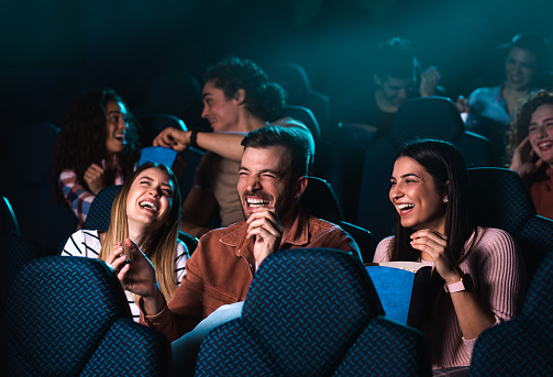 Grupo de personas alegres riendo mientras ven películas en el cine. photo