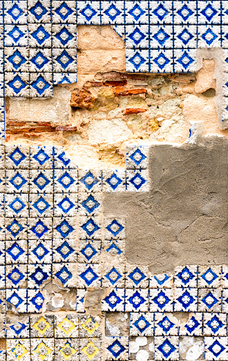 A heavily weathered exterior wall on an apartment building in Lisbon, Portugal, with missing tiles and brickwork.
