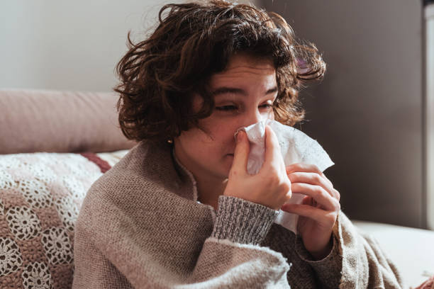 istock young woman blowing her nose 1365386596