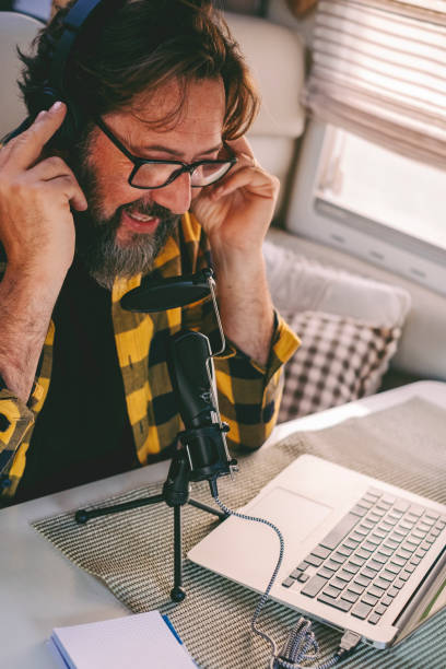 concepto de trabajo de portátil moderno. hombre adulto joven que cuenta y graba en el micrófono con conexión a internet de la computadora para crear contenido web en el canal de podcast. trabajo inteligente en línea - mobile home audio fotografías e imágenes de stock