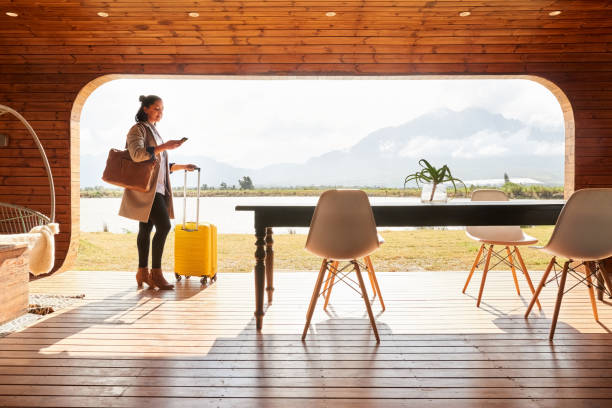 istock Young woman with a suitcase using her phone at her vacation rental 1365390798