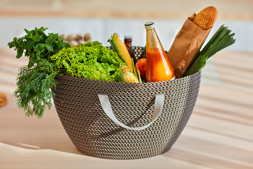 a shopping basket on sunlit kitchen countertop, full of tasty fresh food