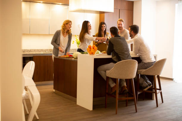istock Group of young people preparing meal, drinking white wine and having a good time 1365396478