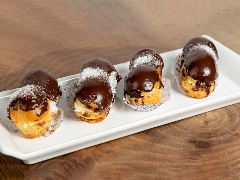 chocolate eclairs on white plate on wood