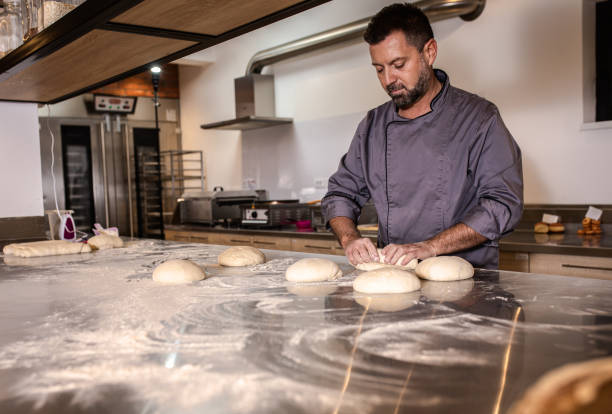 istock Male baker preparing dough for bread in modern manufacturing. 1365399963