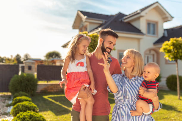 Family holding keys after buying a new house Beautiful happy family standing in front of their new house, parnets holding children and keys happy family with key of their new house stock pictures, royalty-free photos & images