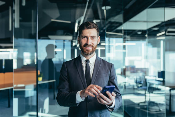 istock Happy and smiling businessman having fun using phone, typing messages on phone, smiling and looking at camera, close-up portrait 1365401210