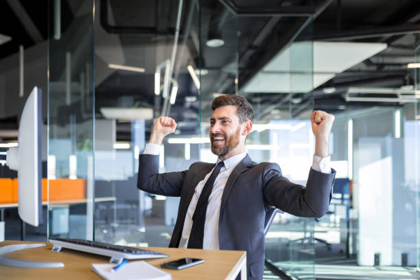 istock Successful seo man, boss business man, celebrates victory by working on computer in modern office 1365402193