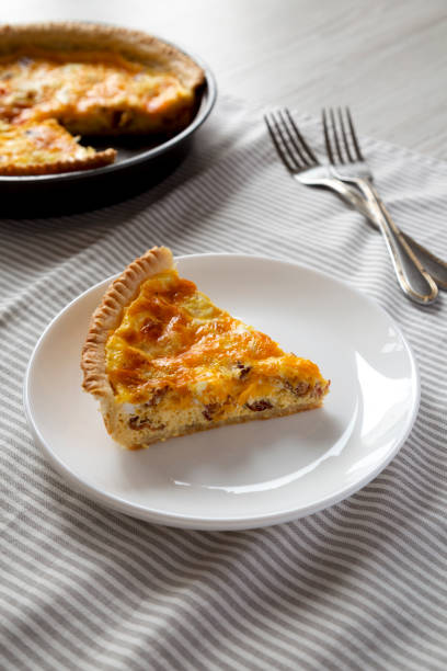 istock Homemade Bacon Quiche with Eggs and Cheddar Cheese on a white plate, side view. 1365402198
