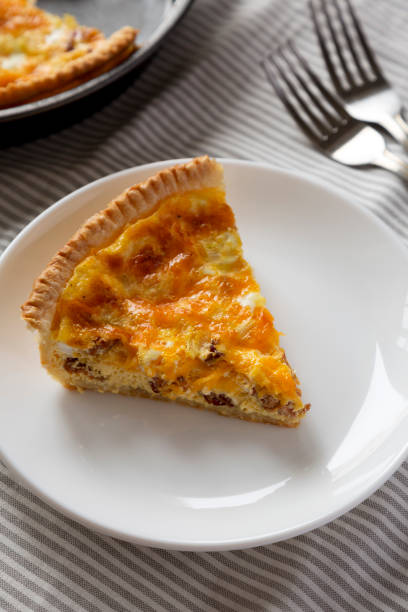 istock Homemade Bacon Quiche with Eggs and Cheddar Cheese on a white plate, side view. 1365402334