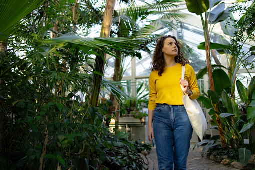 Young Caucasian woman walking trough a lush botanical garden, enjoying herself