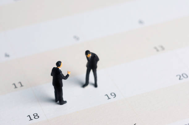 istock Selective focus miniature businessman standing on calendar checking schedule. 1365404068