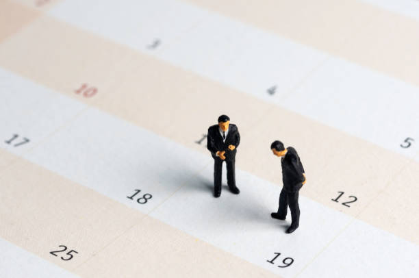 istock Selective focus miniature businessman standing on calendar checking schedule. 1365404615