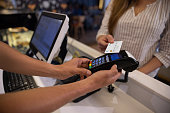 Close-up on a woman making a contactless payment at a cafe