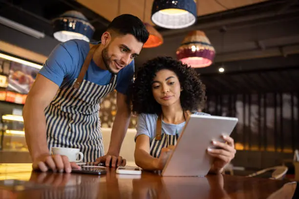 Team of waiters working at a restaurant and looking at the menu on a tablet - food service occupation concepts