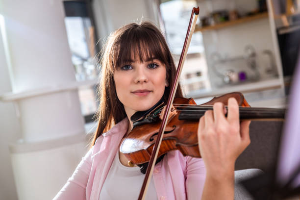 istock Young woman playing the violin at home. 1365405087