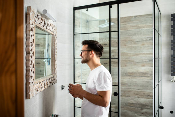 istock Young man going through morning routine in the bathroom applying face cream. 1365406265