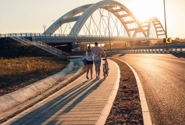 istock Young couple with bicycle enjoying walking at sunset. 1365406479