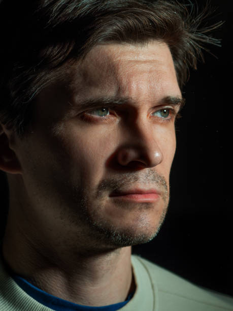 istock A thoughtful sad man looks to the right. portrait in side light, 1365407571
