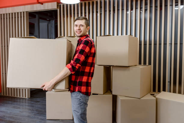 istock Young man, a courier, is carrying a cardboard box in a post office store. 1365408345