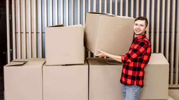 istock Young man, a courier, is carrying a cardboard box in a post office store. 1365409014