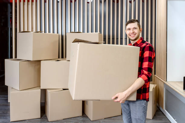 istock Young man, a courier, is carrying a cardboard box in a post office store. 1365409177