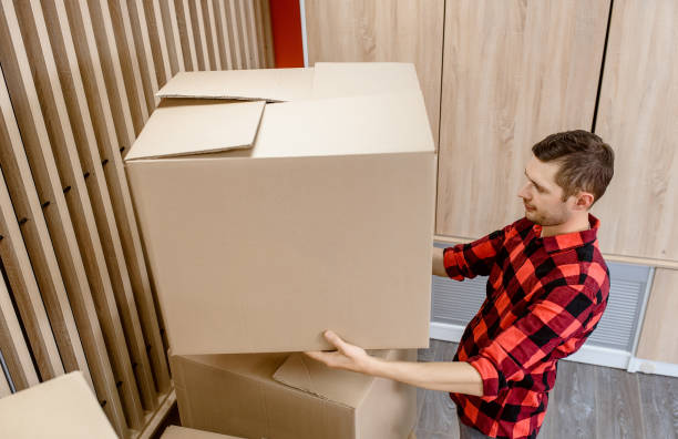 istock Young man, a courier, is carrying a cardboard box in a post office store. 1365409192