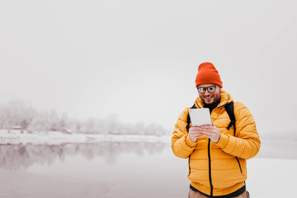 istock Man using digital tablet and walking in snowy nature 1365409448