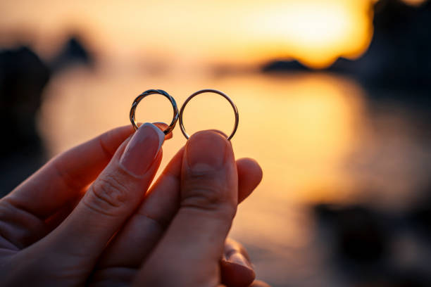 Couple holding their wedding ring on the beach at sunset