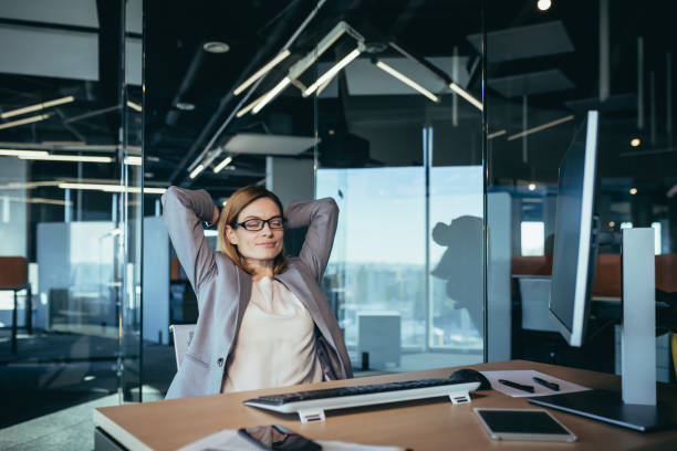 istock business owner woman resting during working hours puts her hands behind her head, thinks about business plans, works in a modern office 1365410481