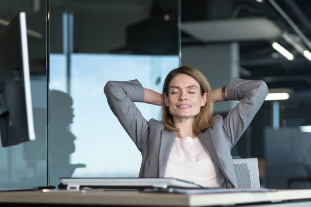 istock business owner woman resting during working hours puts her hands behind her head, thinks about business plans, works in a modern office 1365410482