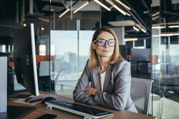 porträt einer vernünftigen und fairen erfolgreichen frau, geschäftsfrau, die in einem modernen büro arbeitet, am computer, selbstbewusst und fokussiert - women serious mature adult business stock-fotos und bilder