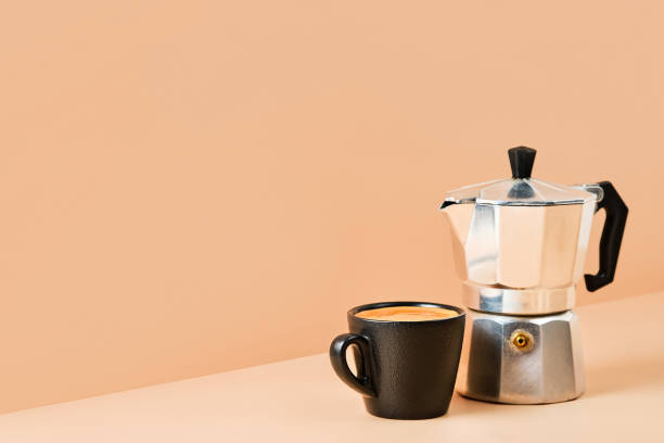 istock Cup with espresso coffee and coffee pot on colored background with copy space for text. Italian style coffee idea for breakfast. Coffee with foam in a black cup. 1365410876