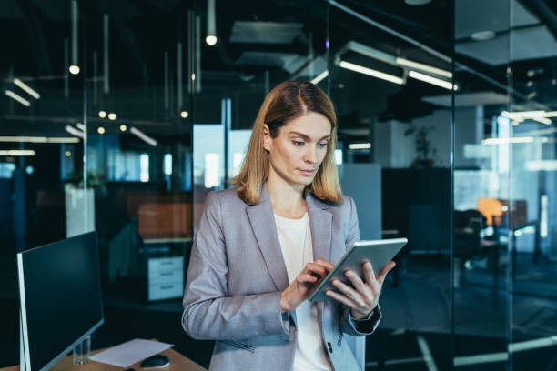 istock Business woman successfully uses a tablet computer in a modern office, a confident manager and focused on work 1365410915