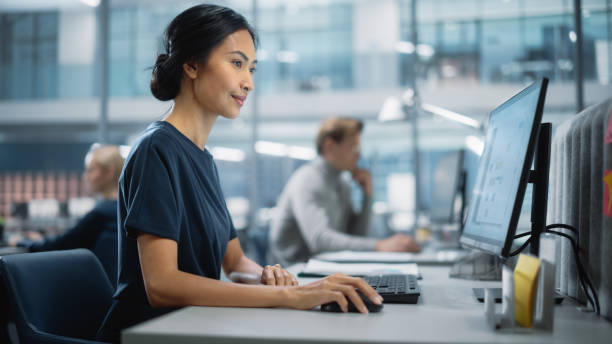 istock In Big Corporate Office: Portrait of Confident Beautiful Asian Manager Using Computer, Businesspeople and Experts Working Around Her, Analysing Statistics, Commerce Data, Marketing Plans. 1365412551