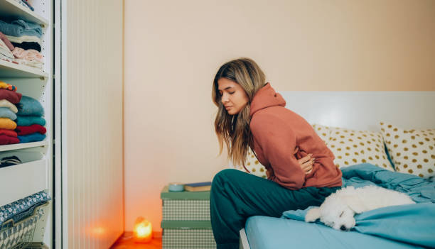 Woman with stomach pain staying home Young woman with painful menstruation resting in bed pms photos stock pictures, royalty-free photos & images