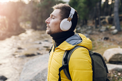 traveler man hiking, with headphones listening to music in the forest