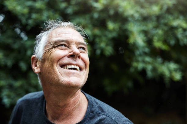 Handsome man in his 50s looks up, smiling and joyful stock photo
