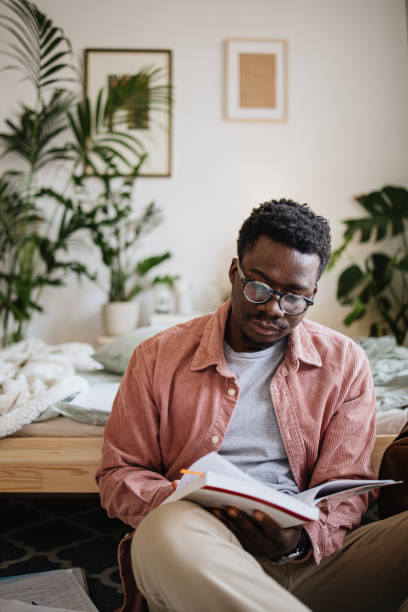 Young student sitting on the floor and reading book for his exam