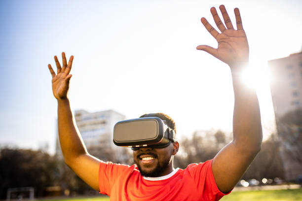 happy man in virtual reality glasses in football field background is blurred concept of virtual reality outdoors summer sunny day
